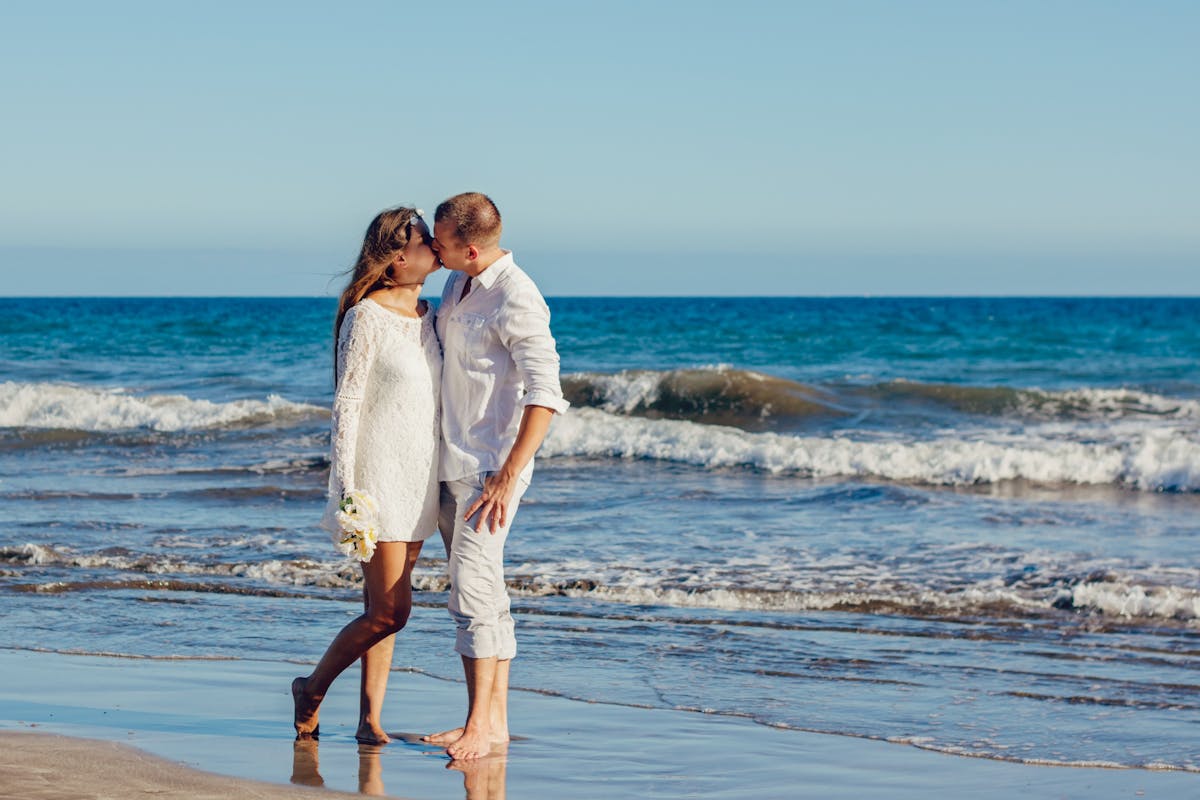 What are the elements that define an all white wedding_couple celebrating love on the beach