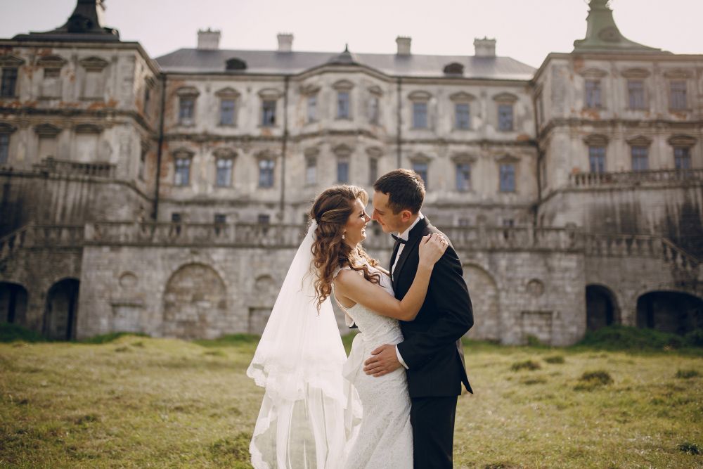Victorian-wedding-couple-leaning-for-a-kiss-in-front-of-an-old-castle