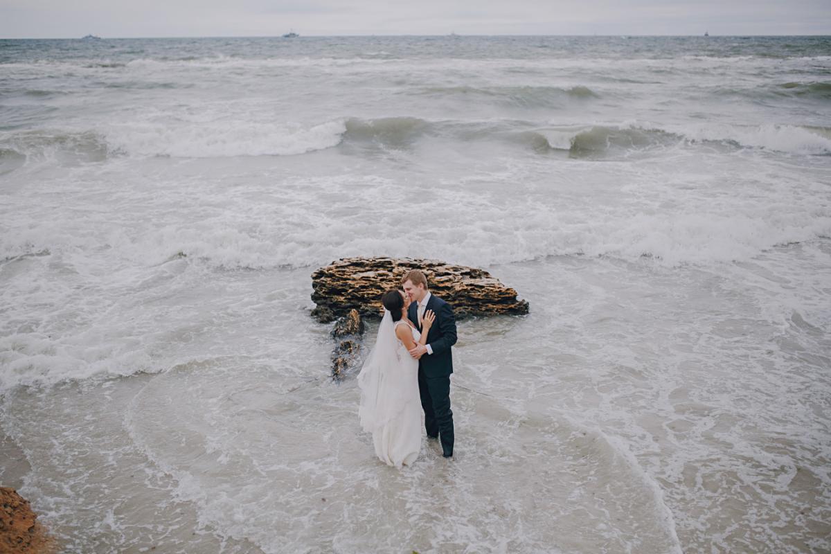 How-to-prepare-for-rain-on-wedding-day-couple-kissing-sea-cloudy