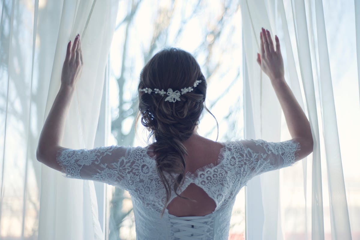 Why should you consider an elegant all white wedding decor_bride in white lace dress looking outside the window